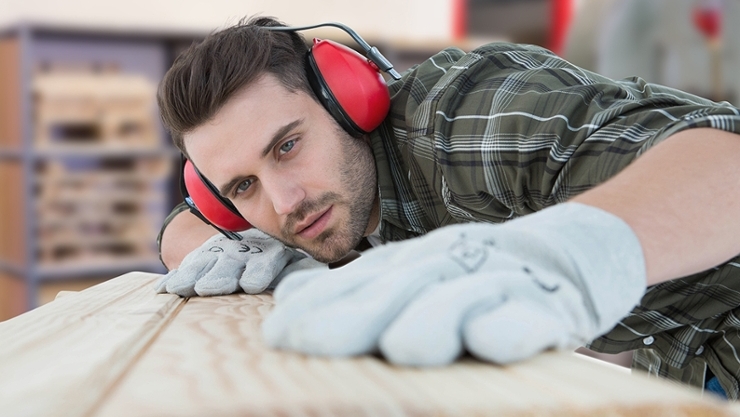 © iStock | Wavebreakmedia Arbeiter mit Hörschutz inspiziert Holzbrett