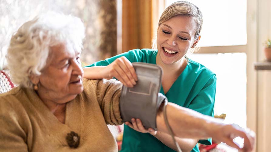 Pflegekraft versorgt Seniorin