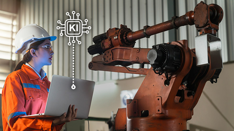 Woman in work clothes stands next to an industrial robot with a laptop